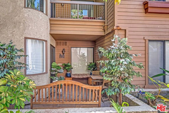 Front view of a multi-story building with a small patio area and plants.