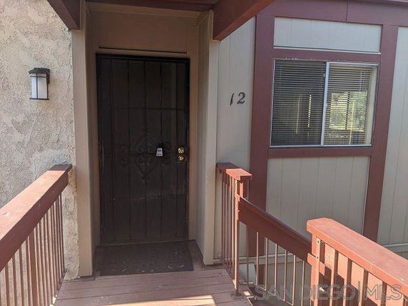 Front view of a house with a wooden entrance pathway and a door with iron bars.