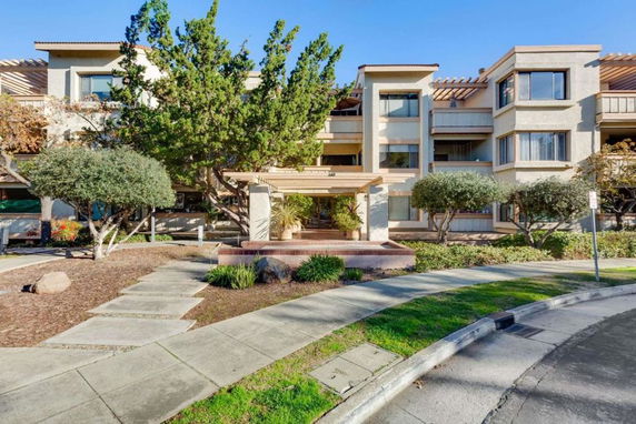 Front view of a multi-story residential building with a landscaped entrance.