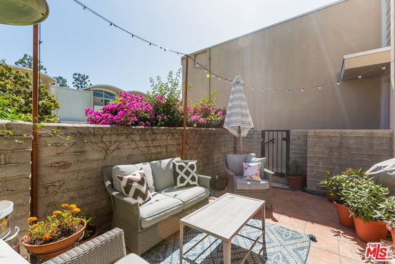 Outdoor patio area with seating, plants, and string lights.