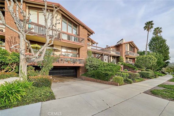Front view of a multi-story residential building with balconies and a garage entrance.