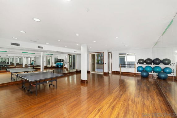 Interior view of a recreation area with a ping pong table and exercise equipment.