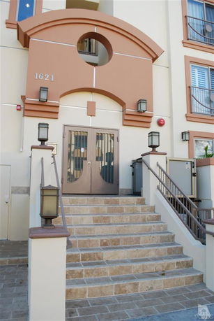 Front view of a building entrance with stairs leading up to a gated doorway.