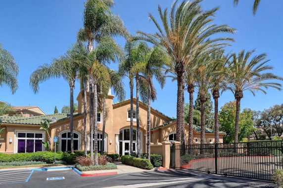 Front view of a building with arched windows and palm trees.