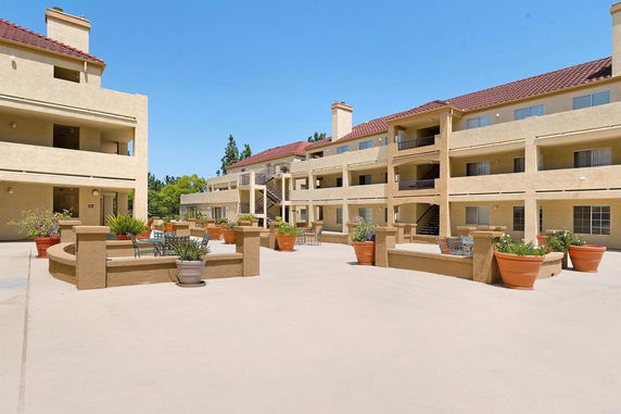 Front view of a multi-story apartment building with red roofs and balconies.