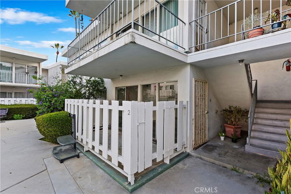 Front view of a two-story building with balconies and a fenced patio area.