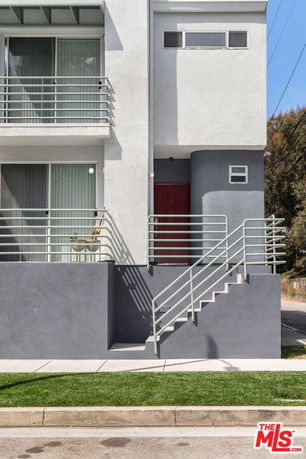 Front view of a modern multi-story building with a staircase and balconies.
