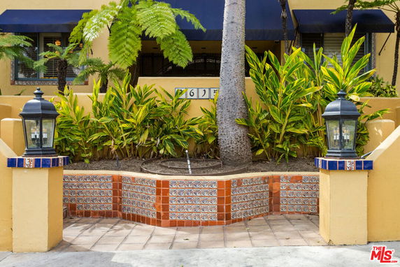 Front view of a yellow building with decorative tiles and plants.