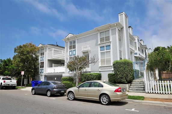 Front view of a multi-story residential building with white siding and balconies.