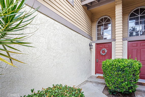 Front view of a house entrance with red doors and arched windows.