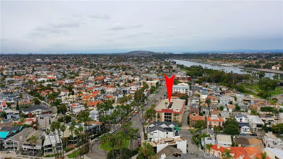 Wide-angle view of a cityscape with a red arrow pointing to a specific building.