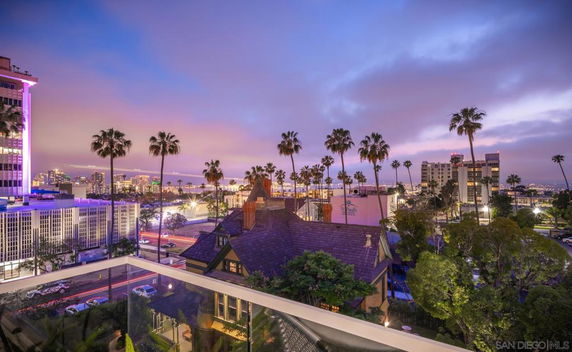 Panoramic view of a cityscape with tall buildings and palm trees at dusk.