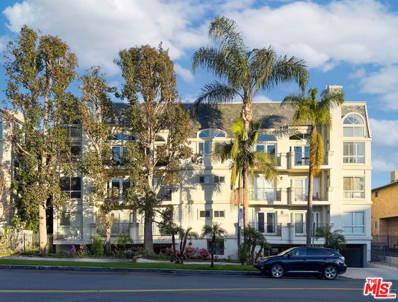 Front view of a multi-story residential building with balconies and arched windows.