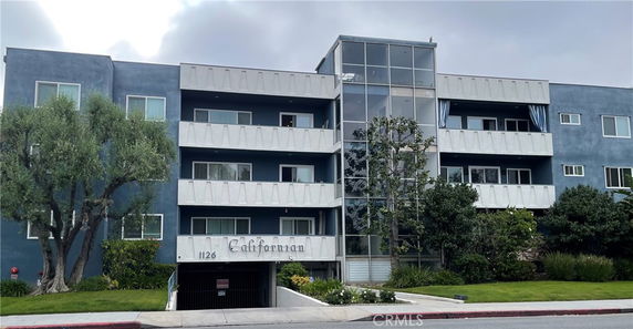 Front view of a multi-story residential building with balconies and blue exterior walls.