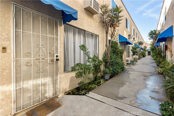 Exterior corridor of an apartment building with blue awnings and plants