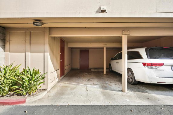 Covered parking area with a parked white vehicle.