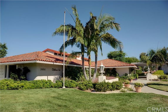 Front view of a single-story building with a red tile roof and a manicured lawn.