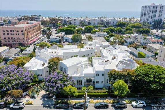 Aerial view of a coastal neighborhood with white buildings and the ocean in the background.
