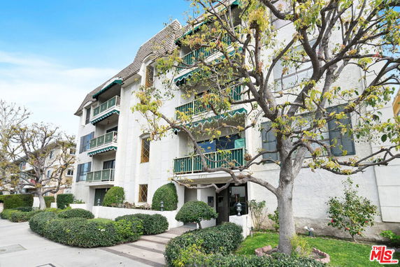 Front view of a multi-story building with balconies and green awnings.