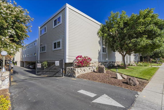Front view of a multi-story residential building with a gated parking entrance.
