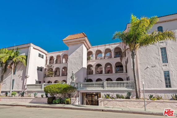 Front view of a multi-story building with arched balconies and a tiled roof.