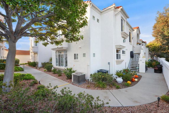Front view of a white multi-story house with architectural details and landscaping.