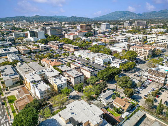 Wide angle view of a cityscape with various buildings and mountains in the distance.