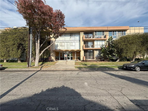 Front view of a three-story building with balconies and a central entrance.