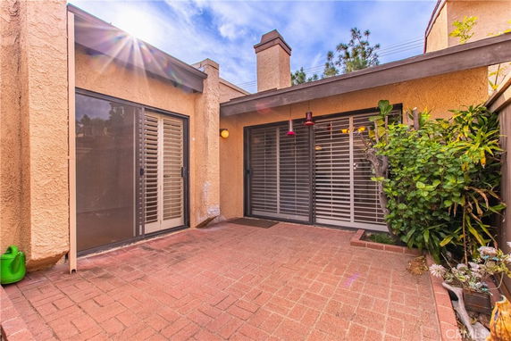 View of patio area with sliding doors and small garden