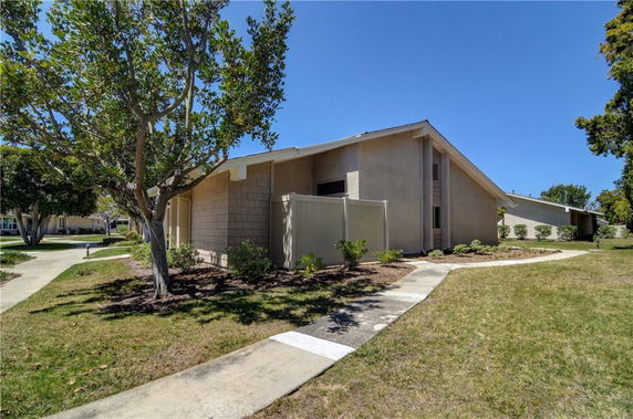 Front view of a single-story house with a sloped roof and fenced area.