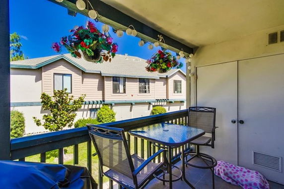 Balcony view showing the exterior of a neighboring building with hanging plants and outdoor furniture.