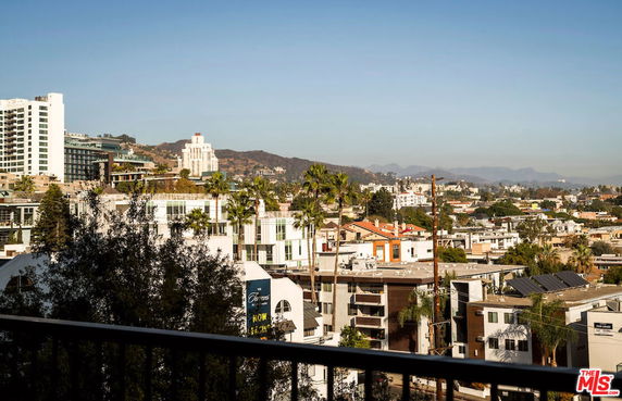 Panoramic view of a cityscape with various buildings and distant hills.