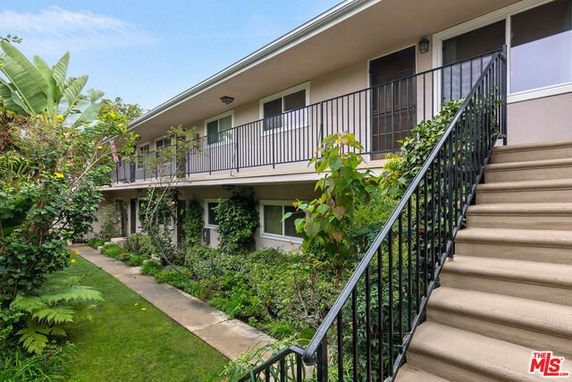 Front view of a two-story building with a staircase and garden.