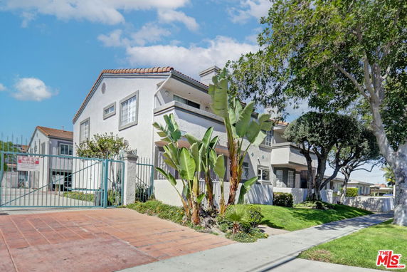 Front view of a multi-story residential building with a gated entrance and tiled roof.