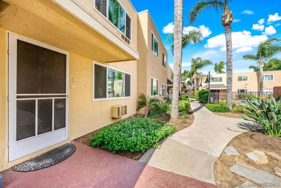 Front view of a two-story apartment building with a walkway and plants.
