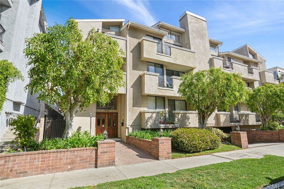 Front view of a multi-story residential building with balconies and brick boundary.