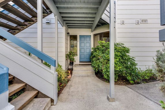 Front view of a house entrance with a blue door and stairs leading up.