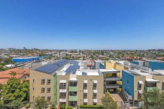 Panoramic view of urban area with buildings and solar panels on rooftops.