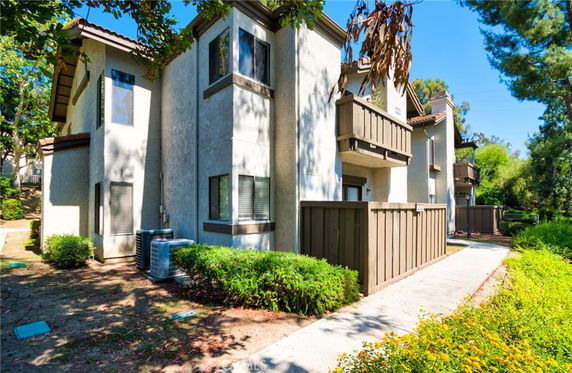 Front view of a multi-story residential building with balconies and a fenced area.