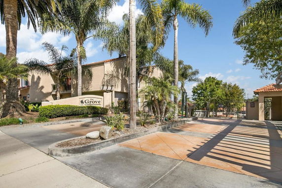 Front view of a condominium complex with palm trees and entrance gate.