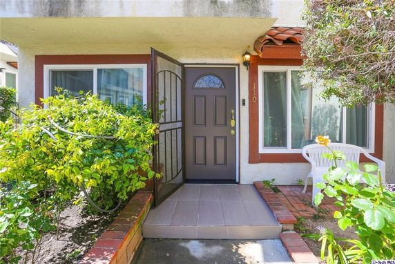 Front view of a house entrance with a dark door and two windows on a patio.