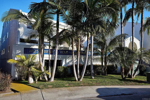 Front view of a building with tropical trees and bushes.