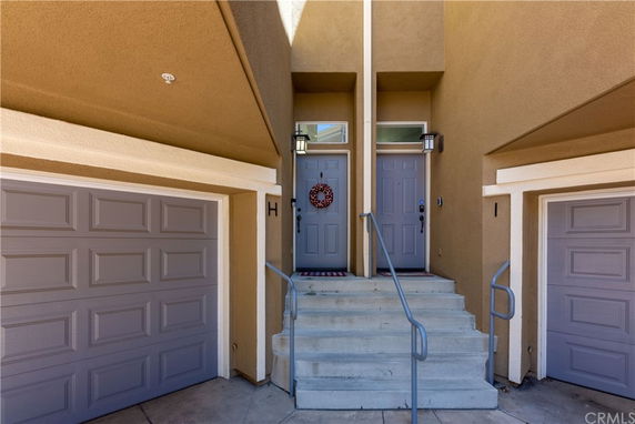 Front view of a house with two entrances, featuring steps and adjacent double garages.