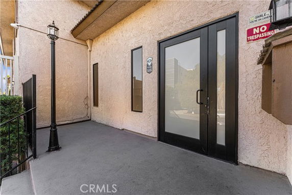 Front view of a building entrance with glass doors and a lamp post.