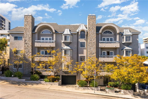 Front view of a multi-story residential building with stone accents and arched windows.
