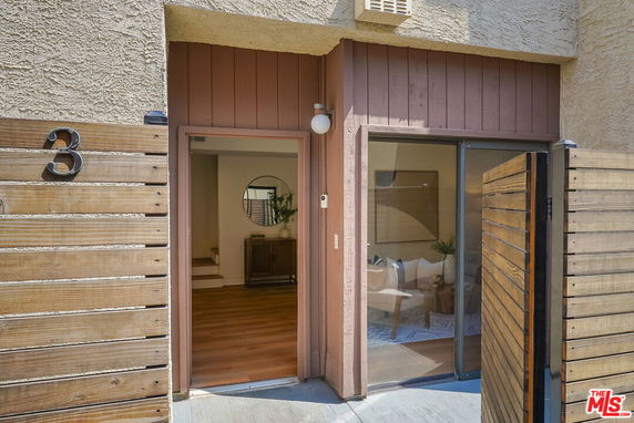 Front view of an entrance to a building with a wooden gate and house number 3.