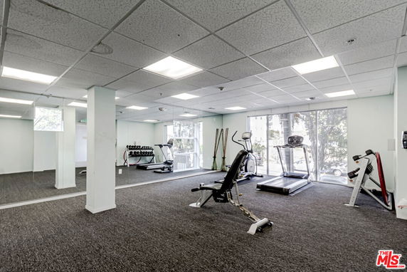 Indoor gym area with exercise equipment and large windows.
