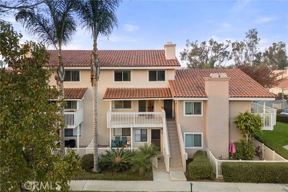 Front view of a two-story house with a red tile roof and balconies.