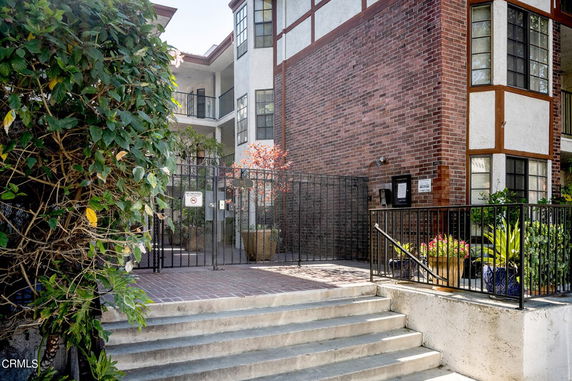Front view of a brick apartment building with gated entry.