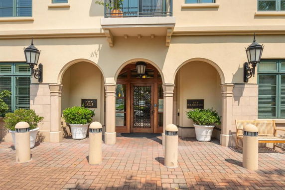 Front view of a building with arched doorways and ornate lamps.